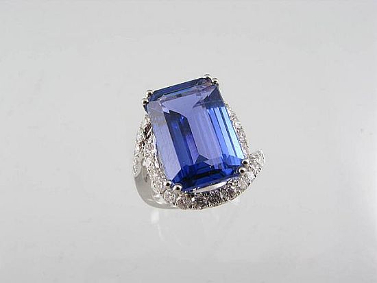 Lot 246. AN EMERALD-CUT TANZANITE RING claw set in 18ct white gold within 28 diamonds. <br>Est $4000-4500